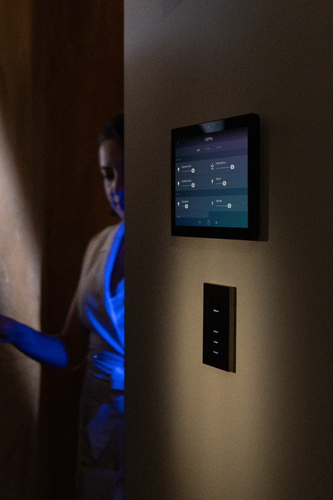 Wall-mounted home-control touchscreen and scene keypad illuminated in a dim interior