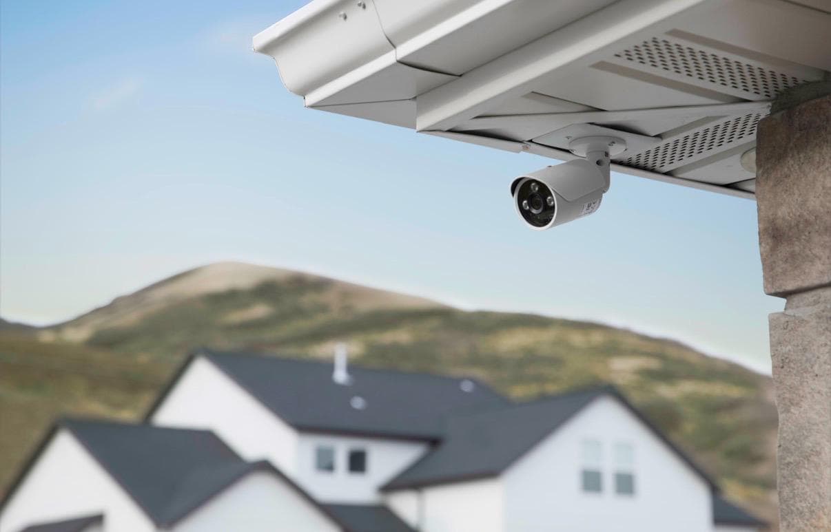 Exterior security camera mounted beneath the eaves of a home